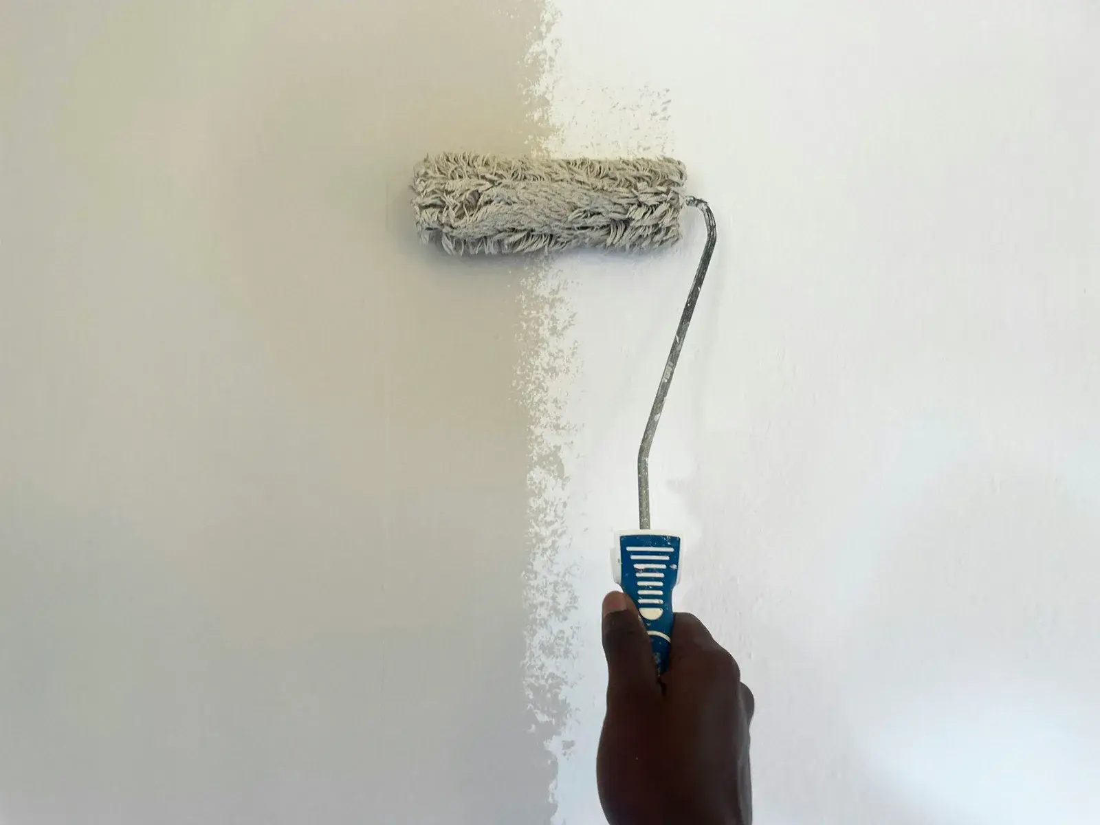 Aplicació de pintura blanca amb corró en una paret interior